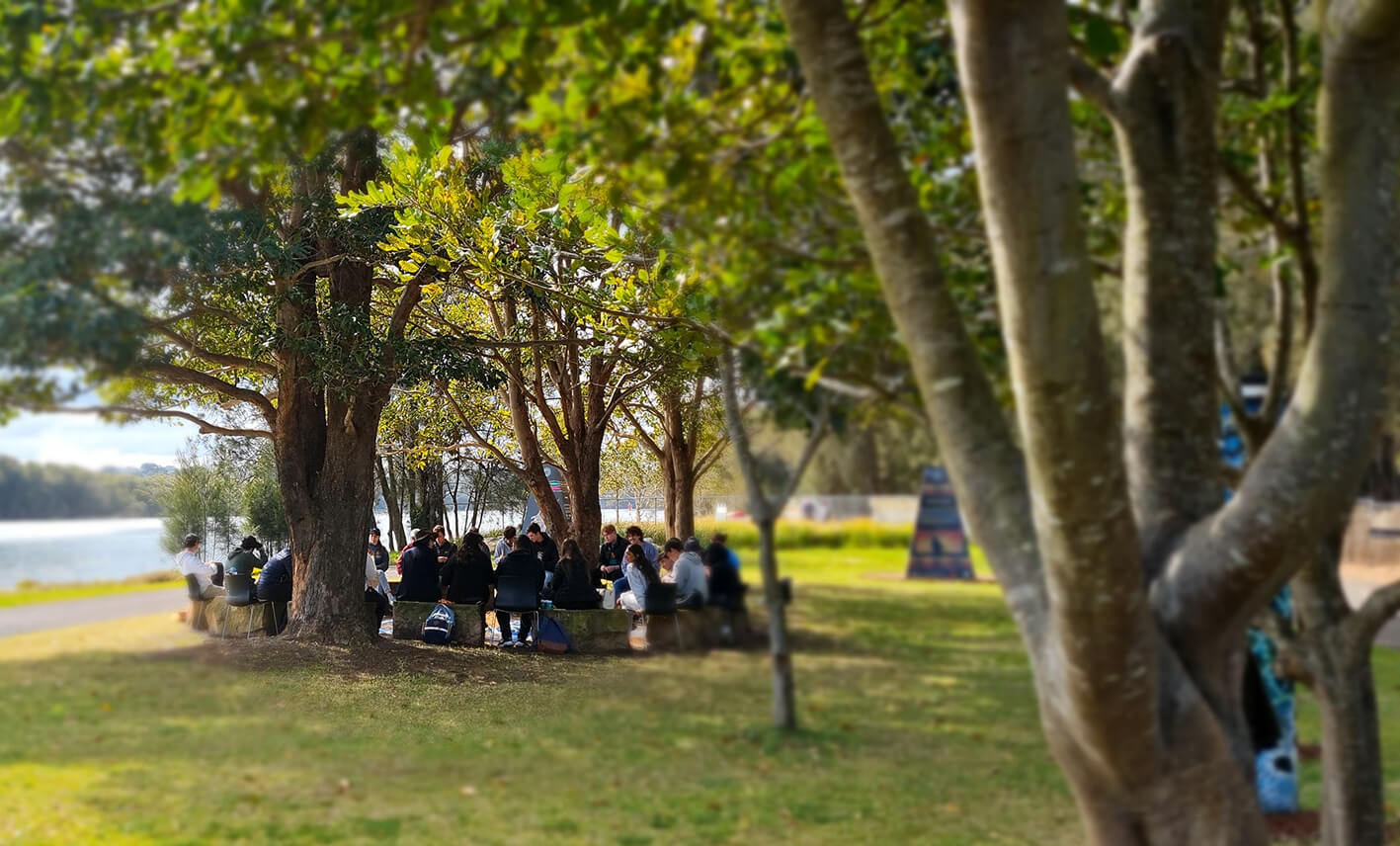 People sitting under a tree in Yarning Circle at Murama